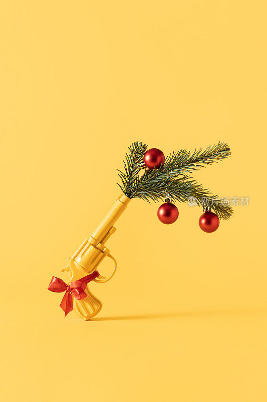 黄色的枪配上绿色的圣诞树树枝、装饰品和红色的球。Party New Year 2023最小概念背景。概念上的静物